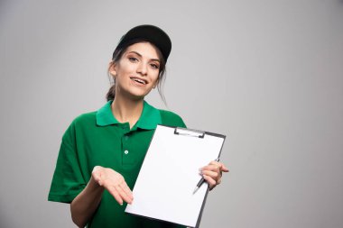 Gri arka planda poz veren teslimatçı kadın. Yüksek kalite fotoğraf