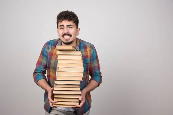 Genç Adam Gri Bir Duvarda Bir Sürü Kitap Tutuyor Yüksek — Stok fotoğraf