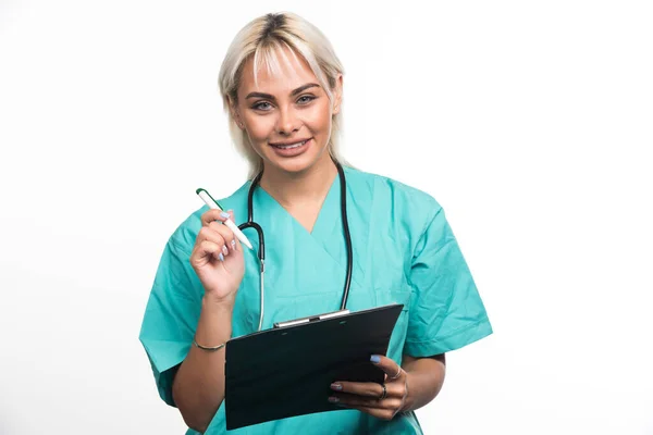 白い背景にペンでクリップボードに何かを書いている女性医師 高品質の写真 — ストック写真