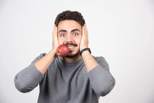 灰色のトレーナーの若い男がリンゴを口の中に持っている 高品質の写真 — ストック写真
