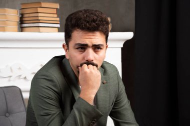 Sakallı genç yakışıklı bir adam, bir soru hakkında endişeleniyor, eli çenesinde endişeli ve gergin. Yüksek kalite fotoğraf