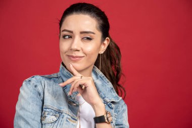 Kırmızı arka planda poz veren kot ceketli güzel bir kadın. Yüksek kalite fotoğraf