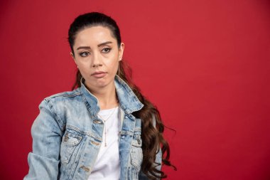 Kırmızı arka planda kot ceketle poz veren güzel bir kadın. Yüksek kalite fotoğraf