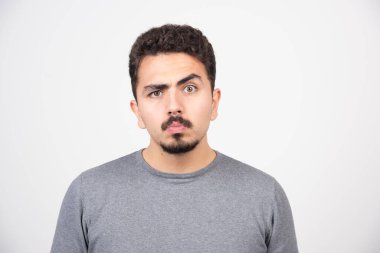 Beyaz bir duvarın üzerinde duran ve poz veren genç bir adam. Yüksek kalite fotoğraf