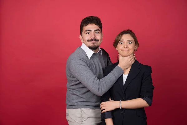 Jovem Brincalhão Estrangula Mulher Fundo Vermelho Foto Alta Qualidade — Fotografia de Stock