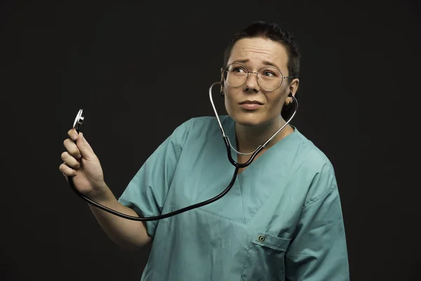 聴診器を持ち患者の声を聞く緑色の制服を着た女医 高品質の写真 — ストック写真