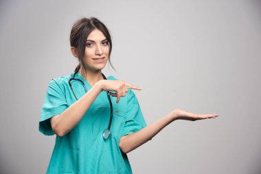 Gri arka planda poz veren üniformalı kadın doktor. Yüksek kalite fotoğraf