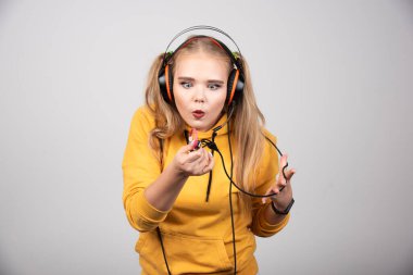 Sarı kazaklı kadın kulaklık tellerine bakıyor. Yüksek kalite fotoğraf