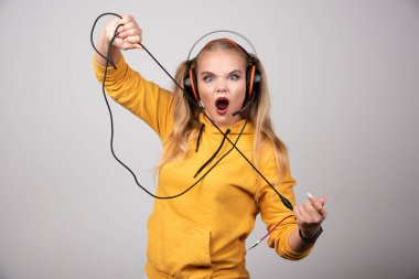 Sarı kapüşonlu komik genç kız kulaklıkla poz veriyor. Yüksek kalite fotoğraf