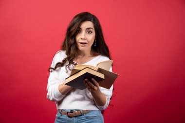 Kırmızı arka planda ilginç bir kitap okuyan genç bir kadın. Yüksek kalite fotoğraf