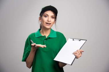 Elinde dosya tutan yeşil üniformalı bir teslimatçı kadın. Yüksek kalite fotoğraf