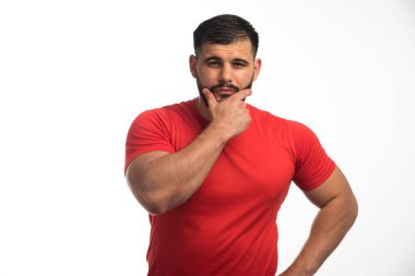 Kırmızı gömlekli sporcu kol kaslarını gösteriyor ve kendinden emin görünüyor. Yüksek kalite fotoğraf
