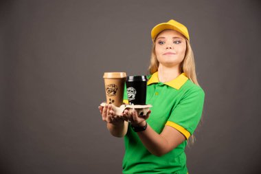 Teslimatçı kadın arka planda bir fincan kahve veriyor. Yüksek kalite fotoğraf