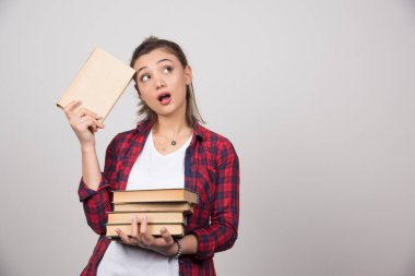 Elinde bir yığın kitap tutan dalgın genç bir öğrencinin fotoğrafı. Yüksek kalite fotoğraf