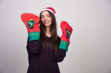 Noel Baba şapkalı ve eldivenli güzel bir kadın mutlu bir şekilde gülümsüyor. Yüksek kalite fotoğraf