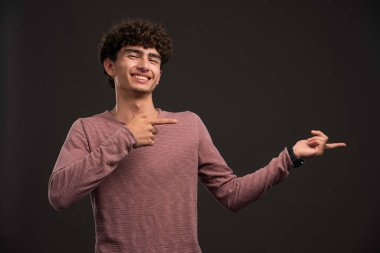 Kıvırcık saçlı genç bir çocuk bir şey sunuyor. Yüksek kalite fotoğraf