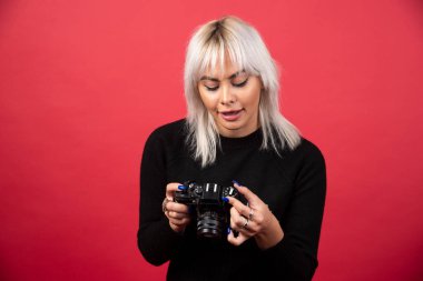 Kırmızı arka planda kameraya bakan genç bir kadın. Yüksek kalite fotoğraf