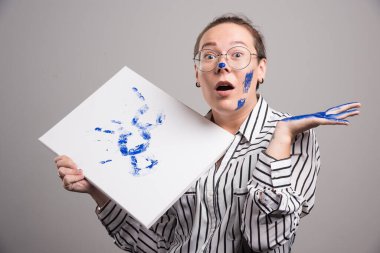 Elinde resim bezi olan bir kadın elini gri arka planda tutuyor. Yüksek kalite fotoğraf