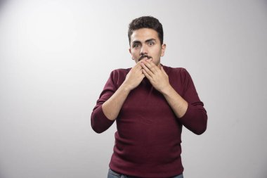 Genç esmer bir adam ağzını kapatıp poz veriyor. Yüksek kalite fotoğraf