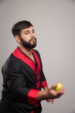 Siyah arka planda bir elma tutan genç adam. Yüksek kalite fotoğraf