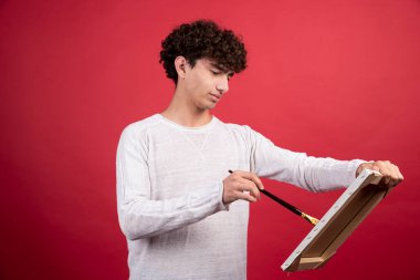 Kıvırcık ressam tuvale bir şeyler çiziyor. Yüksek kalite fotoğraf