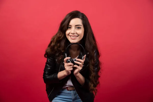 Mujer Joven Sosteniendo Auriculares Posando Sobre Fondo Rojo Foto Alta — Foto de Stock