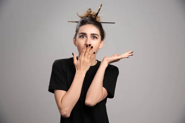 Young woman with messy bun covering her mouth. High quality photo