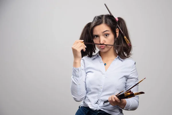 Junge Künstlerin Mit Pinseln Posiert Auf Grauem Hintergrund Hochwertige Illustration — Stockfoto