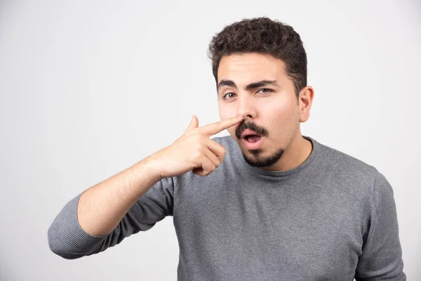 Een Jongeman Die Zijn Neus Een Witte Muur Krabt Hoge — Stockfoto