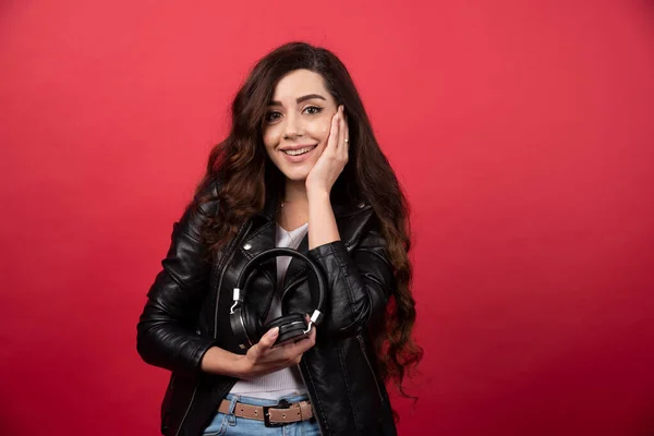 Mujer Joven Sosteniendo Auriculares Posando Sobre Fondo Rojo Foto Alta — Foto de Stock