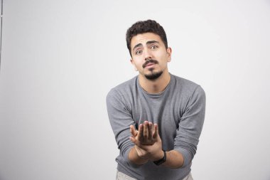 Elleri beyaz duvarda poz veren genç bir adam. Yüksek kalite fotoğraf