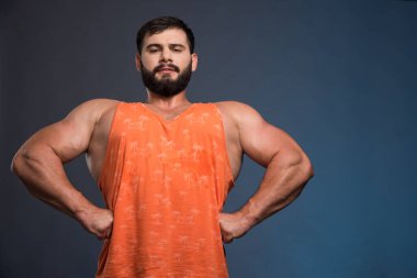 Genç adam koyu mavi arka planda kaslarını gösteriyor. Yüksek kalite fotoğraf