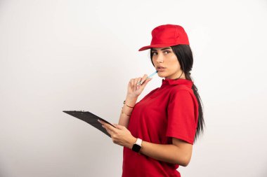 Beyaz arka planda elinde kalem ve not panosuyla duran kadın kurye. Yüksek kalite fotoğraf