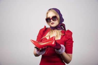 Kırmızı elbiseli çekici kadın bir çift topuklu ayakkabı tutuyor. Yüksek kalite fotoğraf