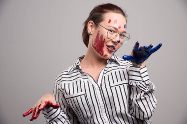 Gri arka planda yüzü boyalı poz veren kadın. Yüksek kalite fotoğraf