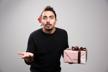 Noel Baba şapkalı genç bir adam elinde yeni yıl hediyesi tutuyor. Yüksek kalite fotoğraf