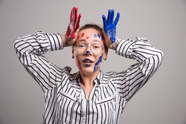 Gri arka planda yüzü boyalı poz veren kadın. Yüksek kalite fotoğraf