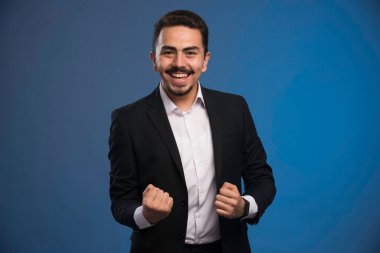 Siyah takım elbiseli bir iş adamı şans işareti yapar. Yüksek kalite fotoğraf