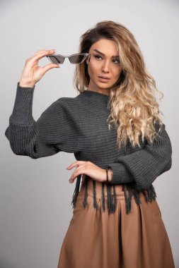 Gri arka planda yoğun bir şekilde gözlüğe bakan genç bir kadın. Yüksek kalite fotoğraf