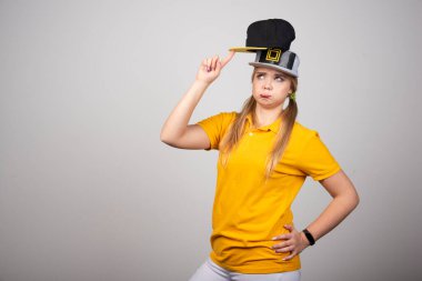 Gri arka planda poz veren iki şapkalı genç bir kız. Yüksek kalite fotoğraf