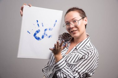 Gri arka planda el resmi gösteren bir kadın. 