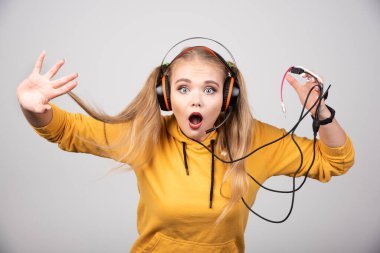 Sarı kapüşonlu sevimli kadın kulaklıkla müzik dinliyor. Yüksek kalite fotoğraf