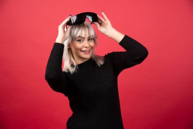 Kırmızı arka planda siyah gözlük takan kadın portresi. Yüksek kalite fotoğraf.