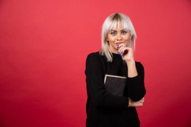 Kırmızı arka plan üzerine kitap tutan genç bir kadın model. Yüksek kalite fotoğraf