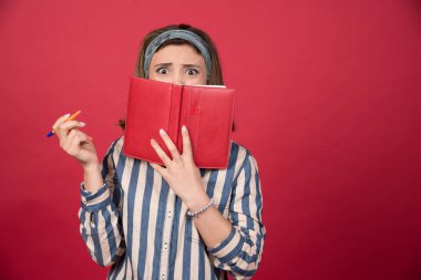 Kitabın arkasına saklanan ve önüne bakan genç bir kız. Yüksek kalite fotoğraf