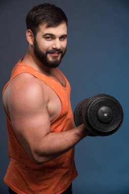 Koyu mavi arka planda dambılı tutan güçlü bir adam. Yüksek kalite fotoğraf