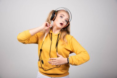 Kulaklıklı sarışın kadın karnını tutuyor. Yüksek kalite fotoğraf