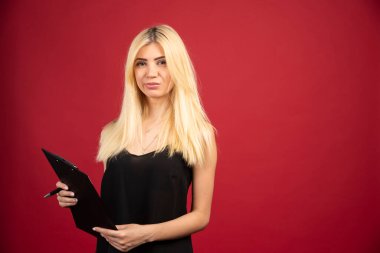 Gülümseyen bir çalışan kırmızı arka planda pano ile poz veriyor. Yüksek kalite fotoğraf