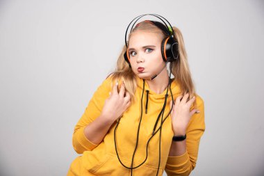 Sarı kazaklı kadın gri arka planda neşeli bir yüz yapıyor. Yüksek kalite fotoğraf