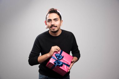 Noel Baba şapkalı genç bir adam elinde yeni yıl hediyesi tutuyor. Yüksek kalite fotoğraf